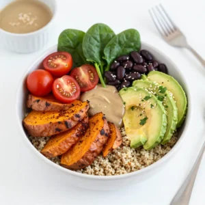 - 1 cup quinoa, rinsed - 2 medium sweet potatoes, peeled and cubed - 1 can (15 oz) black beans, rinsed and drained - 1 ripe avocado, sliced - 1 tablespoon olive oil - 1 teaspoon smoked paprika - &frac12; teaspoon garlic powder - &frac12; teaspoon ground cumin - Salt and freshly ground black pepper, to taste - 1 cup cherry tomatoes, halved - 1 cup fresh spinach or kale, roughly chopped - 2 tablespoons tahini - Juice of 1 fresh lemon - 2 tablespoons water (for tahini sauce, adjust for desired consistency) - Optional toppings: sesame seeds, sliced green onions, or freshly chopped cilantro To create a tasty Sweet Potato Quinoa Buddha Bowl, gather these fresh and simple ingredients. The base is quinoa, a healthy grain that cooks up fluffy. Sweet potatoes add a sweet touch and vibrant color. Black beans pack protein and fiber, while avocado brings creaminess. For flavor, use olive oil, smoked paprika, garlic powder, and ground cumin. These spices add warmth and depth. Salt and pepper balance the dish perfectly. Fresh additions like cherry tomatoes and leafy greens bring brightness. The tahini sauce ties it all together. It&rsquo;s rich, nutty, and full of zest from the lemon juice. You can also add toppings like sesame seeds or green onions for extra crunch. This bowl is not just a meal; it&rsquo;s a celebration of flavors and colors. Enjoy building your Buddha Bowl with these wholesome ingredients! {{ingredient_image_2}} First, you need to boil the water. In a medium pot, bring 2 cups of water to a rolling boil. Once the water is boiling, add 1 cup of rinsed quinoa. Lower the heat to a gentle simmer and cover the pot. Cook for about 15 minutes. The quinoa will absorb all the water. After cooking, remove it from the heat and let it sit for a few minutes. Then, fluff the quinoa with a fork. This makes it light and airy. While the quinoa cooks, let&rsquo;s focus on the sweet potatoes. Preheat your oven to 425&deg;F (220&deg;C). In a large baking sheet, combine 2 medium sweet potatoes that you peeled and cubed. Add 1 tablespoon of olive oil, 1 teaspoon of smoked paprika, &frac12; teaspoon of garlic powder, &frac12; teaspoon of ground cumin, and salt and pepper to taste. Mix the sweet potatoes until they are fully coated. Spread them out in a single layer. Bake for 25 to 30 minutes. Turn them halfway through. They should be tender and have a nice, crispy edge. Now, let&rsquo;s make the tahini sauce. In a small bowl, mix together 2 tablespoons of tahini and the juice of 1 fresh lemon. Add 2 tablespoons of water to this mix. Whisk it all together until the sauce is smooth and creamy. If the sauce feels too thick, add a little more water to reach your desired thickness. This sauce adds a great flavor. Once everything is ready, it's time to build the Buddha bowl. Start with a generous scoop of quinoa as the base. Next, add a scoop of rinsed and drained black beans. Then, add a handful of fresh spinach or kale. On top of that, layer the roasted sweet potatoes, halved cherry tomatoes, and sliced avocado. Finally, drizzle the tahini sauce over the top. Feel free to add optional toppings like sesame seeds, sliced green onions, or fresh cilantro for an extra pop of flavor. Enjoy your vibrant and nutritious meal! - Ensuring perfect quinoa texture: Start with rinsed quinoa. Use two cups of water for one cup of quinoa. Bring the water to a boil before adding quinoa. Cook it on low heat for 15 minutes, then let it sit for a few minutes. Fluff it with a fork for a light texture. - Roasting sweet potatoes for optimal flavor: Cut sweet potatoes into even cubes. Toss them with olive oil and spices. Spread them on a baking sheet. Bake at 425&deg;F for 25 to 30 minutes. Turn them halfway for even cooking. They should be tender and slightly crispy. - Suggested spice additions: For extra flavor, add cayenne pepper for heat. Try adding onion powder for sweetness. A pinch of cinnamon can give warmth. Consider using fresh herbs like thyme or rosemary for a fragrant touch. - Best combinations for tahini sauce: Mix tahini with lemon juice and water. Add garlic powder for a kick. You can also include a bit of maple syrup for sweetness. Adjust water until it reaches your desired consistency. - Alternative beans or greens: You can swap black beans for chickpeas or kidney beans. For greens, consider arugula or Swiss chard. Both options add unique flavors and textures. - Dairy-free and gluten-free options: This recipe is already gluten-free! Ensure your tahini is pure and check for gluten in other ingredients. Use avocado or sunflower seeds as creamy toppings for a dairy-free touch. Pro Tips Cook Quinoa Perfectly: To achieve fluffy quinoa, ensure to rinse it thoroughly before cooking to remove the natural saponins, which can impart a bitter taste. Enhance Sweet Potato Flavor: For extra flavor, consider adding a pinch of cinnamon or cayenne pepper to the sweet potatoes before roasting for a delightful twist. Avocado Ripeness: Choose a ripe avocado for optimal creaminess. If it's not ripe, place it in a brown paper bag with an apple or banana to speed up the ripening process. Adjust Tahini Consistency: When making the tahini sauce, adjust the water based on your preference. For a thicker dressing, use less water; for a pourable sauce, add more. {{image_4}} You can boost the protein in your Buddha bowl with some simple additions. Tofu and tempeh are great options. - Tofu: Choose firm tofu for a nice texture. Cut it into cubes and pan-fry until golden. - Tempeh: Slice tempeh thinly and marinate it in soy sauce. Then, grill or saut&eacute; until crispy. You can also add other legumes. Chickpeas and lentils work well here. They add protein and fiber. Just toss them in with your black beans for an extra nutrient kick. Seasonal veggies can change the flavor of your bowl. In summer, use fresh zucchini, bell peppers, or corn. These add brightness and crunch. In winter, try root veggies like carrots or parsnips. They add sweetness and warmth to your meal. Roasting them brings out their natural flavors. The tahini sauce is delicious, but you can try other dressings too. - Lemon vinaigrette: Mix olive oil, lemon juice, salt, and pepper for a simple dressing. - Balsamic glaze: Drizzle balsamic glaze over the top for a sweet and tangy flavor. You can make dressings at home or buy them. Homemade options let you control the flavors. Store-bought options are quick and easy. Just find one that fits your taste. To keep your Sweet Potato Quinoa Buddha Bowl fresh, store leftovers in the fridge. Use airtight containers to prevent air from spoiling your meal. This method keeps your bowl tasty for up to four days. If you will eat the leftovers soon, put the quinoa and veggies together. For longer storage, keep the tahini sauce separate. This prevents sogginess and maintains flavor. You can freeze your Buddha bowl, but it's best to freeze the ingredients separately. Freeze the cooked quinoa and roasted sweet potatoes in individual bags. Black beans and veggies can also be frozen. When you're ready to eat, thaw the ingredients in the fridge overnight. Reheat them in the microwave or on the stove until warm. This way, each element stays fresh. To keep your ingredients fresh longer, store them away from moisture. Use paper towels in containers to absorb excess water. For preventing sogginess, keep sauces separate until you eat. This simple step ensures that every bite tastes great. Remember, fresh ingredients lead to a more enjoyable meal. You can use several grains in place of quinoa. Here are some options: - Brown rice - Farro - Bulgur - Barley - Couscous These grains provide similar textures and flavors. Each option adds its own unique taste to your Buddha bowl. Test them out to see which you like best! Yes! You can easily prep this bowl in advance. Here are some meal prep tips: - Cook the quinoa and sweet potatoes a day ahead. - Store them in separate containers in the fridge. - Assemble the bowls the next day for quick meals. - Keep the tahini sauce in a jar for easy use. This method saves time and keeps your meals fresh. Absolutely! This Buddha bowl is fully vegan. Here&rsquo;s why: - Quinoa, sweet potatoes, and black beans are plant-based. - The tahini sauce contains no animal products. - Fresh veggies, like avocado and spinach, add nutrients. You can enjoy this wholesome meal without any animal ingredients. If you want to boost the protein in your Buddha bowl, try these ideas: - Add grilled tofu or tempeh for a hearty protein source. - Consider adding chickpeas or lentils for extra texture. - Sprinkle some hemp seeds on top for a nutty flavor. These options make your meal even more filling and nutritious. This guide covered how to make a delicious Buddha bowl step-by-step. We explored key ingredients like quinoa, sweet potatoes, and avocado, plus seasonings that boost flavor. You learned tips for perfect cooking, variations for taste, and smart storage methods for freshness. Now, you have the tools to make a healthy meal that fits your needs. Enjoy creating your Buddha bowl and share it with others. It&rsquo;s a fun way to eat well!