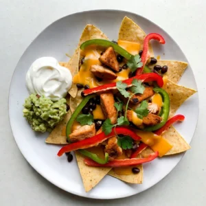 - 1 bag of tortilla chips - 1 pound boneless, skinless chicken breast, thinly sliced - 1 red bell pepper, sliced into strips - 1 green bell pepper, sliced into strips - 1 medium onion, sliced into rings - 2 tablespoons extra-virgin olive oil - 2 teaspoons fajita seasoning (store-bought or homemade) - 1 cup shredded sharp cheddar cheese - 1 cup shredded Monterey Jack cheese - 1 cup canned black beans, drained and thoroughly rinsed - 1 fresh jalape&ntilde;o, sliced (optional for added spice) - Fresh cilantro leaves, roughly chopped, for garnish - Sour cream and guacamole, for serving To make perfect Sheet Pan Fajita Nachos, gather all the ingredients first. This helps keep you organized. You need tortilla chips as the base. Use 1 pound of boneless, skinless chicken breast. Slice it thin for quick cooking. Next, grab a red bell pepper and a green bell pepper. Slice them into strips for a colorful look. A medium onion, sliced into rings, adds sweetness. You also need olive oil to coat the chicken and veggies. Fajita seasoning gives that classic flavor. For the cheese lovers, use sharp cheddar and Monterey Jack cheese. Black beans add protein and texture. If you enjoy heat, slice a fresh jalape&ntilde;o. Lastly, fresh cilantro leaves add a lovely garnish. Serve with sour cream and guacamole for extra creaminess. When you have everything ready, you can start cooking. This recipe is fun, easy, and perfect for sharing. {{ingredient_image_2}} Preheating your oven is key. Set it to 400&deg;F (200&deg;C). This helps nachos bake evenly. A hot oven makes all the difference in cooking time and texture. In a large bowl, toss the chicken, bell peppers, and onion with olive oil and fajita seasoning. Make sure everything is covered well. This step adds great flavor to your filling. Take the seasoned chicken and veggies and spread them on a large sheet pan. Place them evenly across the pan. This ensures the chicken cooks well and the veggies get tender. Roast the mixture in your preheated oven for about 15 to 20 minutes. Check that the chicken reaches 165&deg;F and the veggies are soft and slightly caramelized. This step is vital for taste and texture. Once roasted, remove the pan from the oven. Layer the tortilla chips on top of the chicken and veggie mix. Make sure to cover the base well for a strong nacho foundation. Now, distribute the cooked chicken and veggies over the tortilla chips. This way, every chip gets some tasty toppings. It creates a burst of flavor in each bite. Sprinkle the shredded cheddar and Monterey Jack cheese generously over the nachos. Try to cover all the toppings so you get a cheesy experience. I like to use a mix for depth of flavor. Next, add the drained black beans and sliced jalape&ntilde;os on top. The beans add protein and the jalape&ntilde;os give a nice kick. These layers create a wonderful taste contrast. Return the sheet pan to the oven for another 5 to 7 minutes. Bake until the cheese melts and bubbles up slightly. The cheese should look golden and delicious at this stage. After baking, carefully take the pan out of the oven. Let it cool a bit, then garnish with fresh cilantro. This adds a bright pop of color and freshness to your dish. Serve your nachos hot with bowls of sour cream and guacamole. These dips add creaminess and flavor, making the meal even better. Enjoy! You can make your fajita nachos unique. Here are some topping ideas: - Diced tomatoes - Sliced olives - Corn - Avocado or guacamole - Fresh lime juice - Different types of cheese like pepper jack - Salsa or pico de gallo Feel free to mix and match your favorite flavors. The key is to balance flavors and textures. Having the right tools makes cooking easier. Here&rsquo;s what I recommend: - Large mixing bowl for tossing ingredients - Sheet pan for roasting - Spatula for mixing and serving - Sharp knife for slicing veggies - Measuring spoons for precise seasoning These simple tools help you achieve the best results. To save time, prepare ingredients before you start cooking. Here are some tips: - Slice veggies and chicken in advance. - Preheat the oven while you prep. - Use a timer to track cooking time for each step. - Clean as you go to keep your workspace tidy. These steps make the process quicker and more fun. Pro Tips Use Fresh Ingredients: Fresh vegetables and high-quality chicken will enhance the flavor of your nachos significantly. Opt for organic produce if possible for the best taste. Customize Your Heat: Adjust the spiciness by adding more or fewer jalape&ntilde;os, or even using a spicier cheese. You can also incorporate some hot sauce for an extra kick. Layer Wisely: For a well-balanced nacho experience, layer toppings evenly. This ensures that every chip has a bit of everything, preventing any dry bites. Serve Immediately: Nachos are best enjoyed fresh out of the oven while the cheese is still gooey. Plan to serve them right after baking for maximum enjoyment. {{image_4}} To make vegetarian fajita nachos, swap the chicken for plant-based options. You can use mushrooms or zucchini for a meaty texture. Black beans add protein and fiber. Try using extra cheese or a plant-based cheese for flavor. You can also load up on bell peppers and onions for a fresh crunch. These swaps keep the dish tasty and filling. If you love heat, there are easy ways to spice things up. Add more jalape&ntilde;os or use spicy peppers like serranos. You can also sprinkle some chili powder or cayenne pepper on the chicken and veggies. For a fiery kick, try drizzling hot sauce over the nachos before serving. These options will set your taste buds on fire! You don&rsquo;t have to stick to chicken for your nachos. Try using beef for a heartier flavor. Ground turkey or pork can also work well. If you prefer seafood, shrimp makes a great topping too. Just remember to adjust the cooking time for different proteins. This allows everyone to enjoy their favorite flavors. To keep your fajita nachos fresh, store them in an airtight container. Make sure the nachos have cooled down first. This helps keep them from getting soggy. You can store them in the fridge for up to three days. If you want to enjoy them later, separate the chips from the toppings. This helps maintain the crunchiness of the chips. When reheating, use the oven to keep the nachos crispy. Preheat your oven to 350&deg;F (175&deg;C). Spread the nachos on a baking sheet. Heat them for about 10-15 minutes. You can also cover them with foil to avoid burning. If you want to use the microwave, heat in short bursts of 30 seconds. This method may make the chips a bit soggy, so be careful. Freezing nachos is possible, but I recommend freezing the toppings separately. Place the chicken, veggies, and beans in a freezer-safe bag. Remove as much air as possible, and seal it tight. You can freeze these for up to three months. When you're ready to eat, thaw overnight in the fridge. Reheat the toppings on the stove or in the oven. Serve them over fresh tortilla chips for the best taste. Yes, you can switch cheeses. Here are a few options: - Monterey Jack - Pepper Jack for spice - Queso Blanco for creaminess - Mozzarella for a stretchy texture Try different blends for unique flavors! You can keep leftover nachos for about 2-3 days. Store them in an airtight container. Use foil or plastic wrap to cover the nachos. This helps keep them fresh. Fajita nachos pair well with: - Fresh guacamole - Creamy sour cream - Salsa for added flavor - A side of refried beans - Crispy tortilla strips These sides will enhance your nacho experience! Yes, you can prep fajita nachos in advance. Here are some tips: - Cook the chicken and veggies a day before. - Store them separately from the chips. - Layer everything just before baking. This way, you get fresh nachos quickly! Fajita nachos are a fun, delicious dish. We covered the key ingredients and steps. Preheating the oven ensures perfect cooking. Layer your tacos right to enhance flavor. Explore variations to suit your taste. Remember to store leftovers correctly for later. Finally, making these nachos can bring joy to your table. Try them out and enjoy!